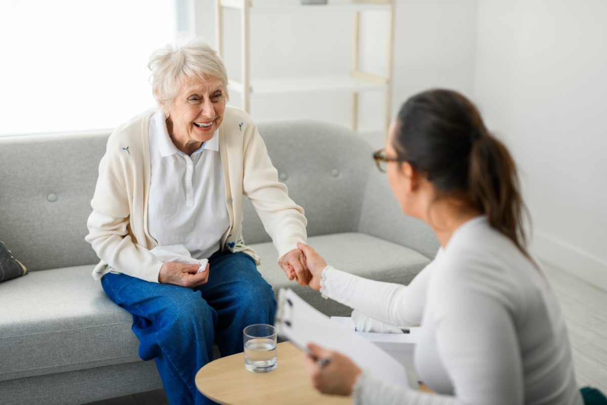 Elderly woman talking with caregiver at home.