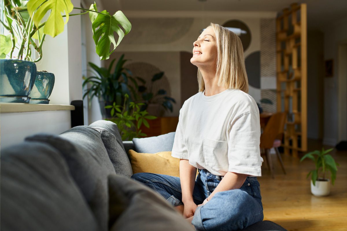 Woman enjoying sunlight in cozy living room.