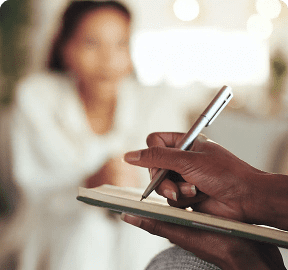 Person writing on notepad during conversation.