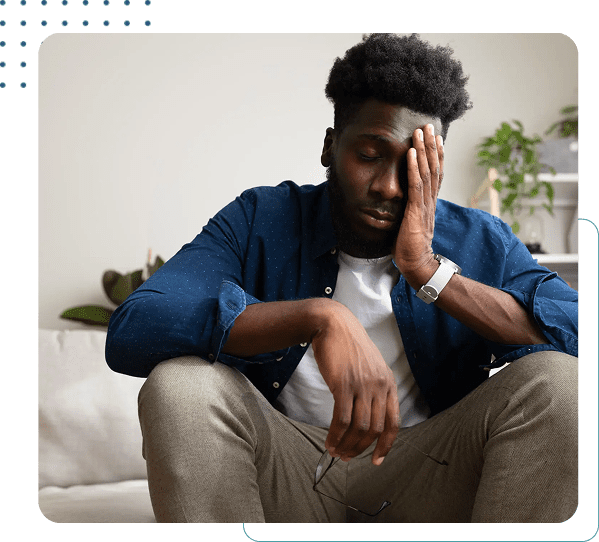 Man sitting, resting hand on face tiredly.