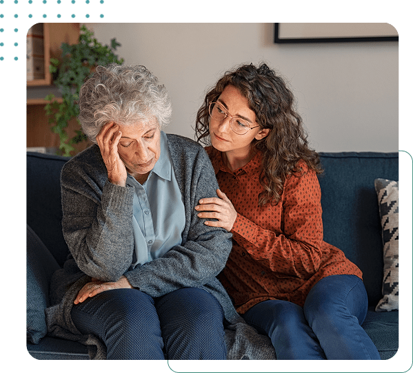 Woman comforting elderly woman on sofa.
