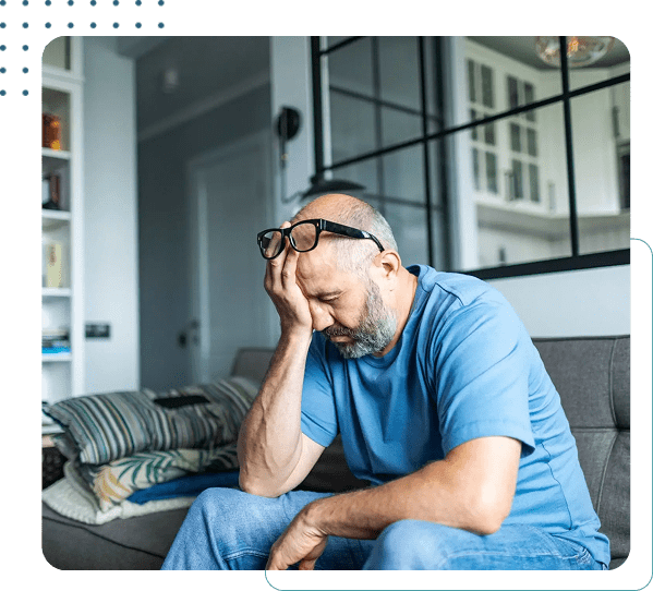 Man sitting on couch, looking stressed.