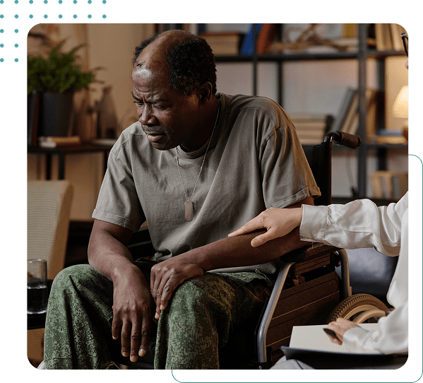 Man in wheelchair being comforted by another.