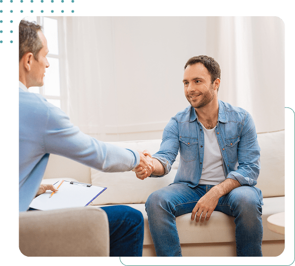 Two men shaking hands on a sofa.