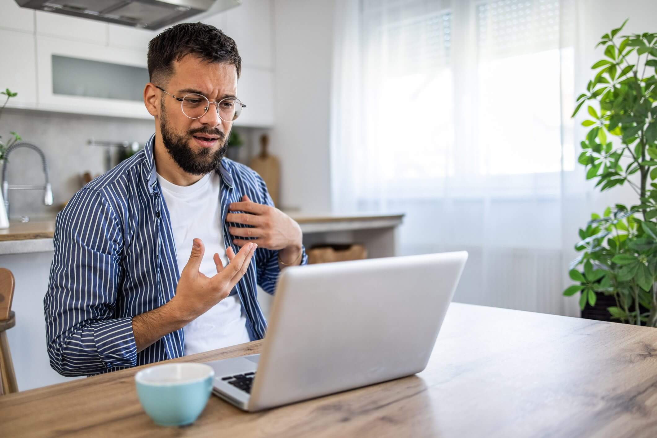 Man gesturing while video calling on laptop.