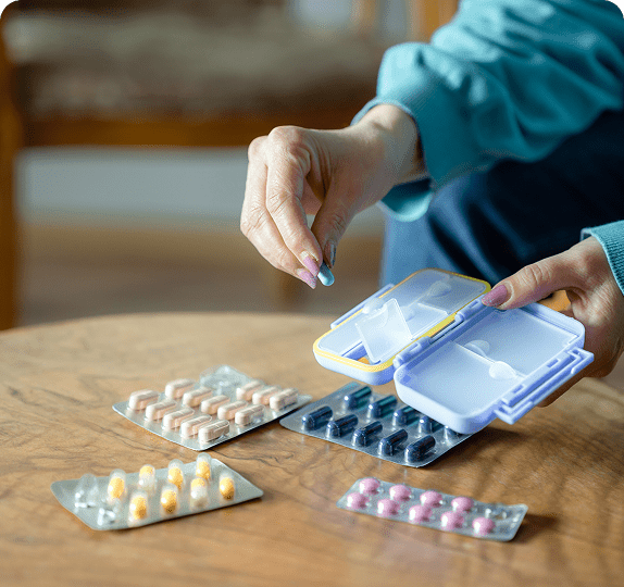 Person organizing pills into a pillbox.