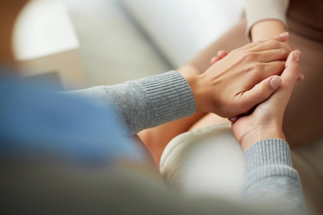 Hands clasped in comforting gesture.
