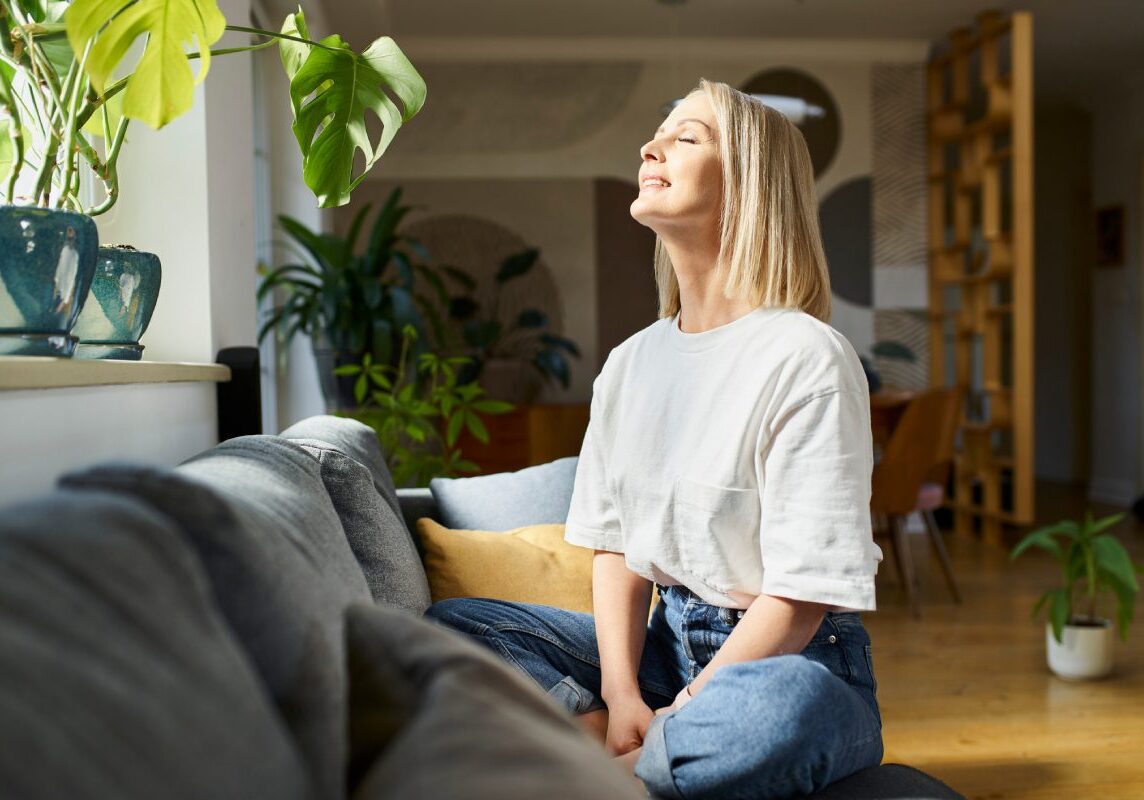 Woman enjoying sunlight in cozy living room.