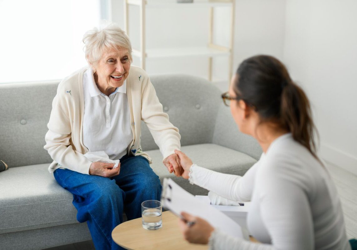 Elderly woman talking with caregiver at home.